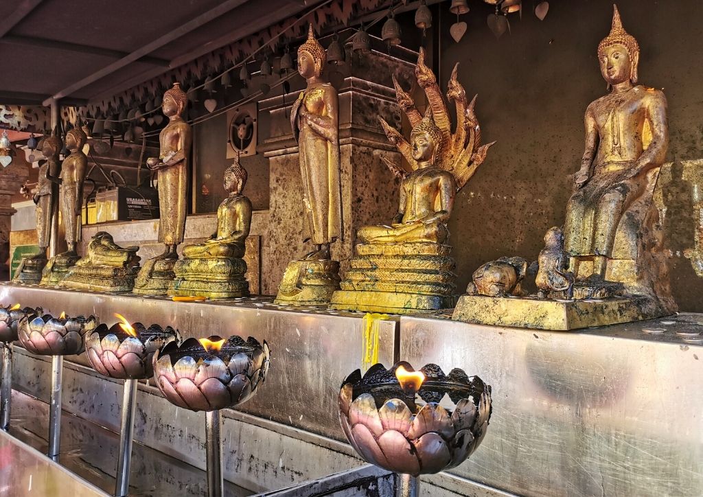 tempio con statue dorate di buddha e fiori di loto in thailandia